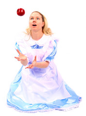 young girl in blue dress catching a falling apple in excitement