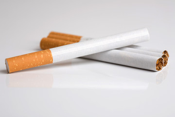 Four cigarettes lying together on shiny surface