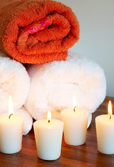 Fototapeta na wymiar Relaxing spa scene with white and orange rolled up towels 