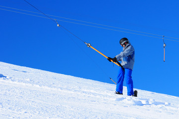 snowboarder on skilift in winter ski resort blue sky