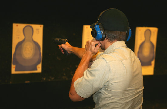 marksman on the range using a flashlight while shooting a pistol