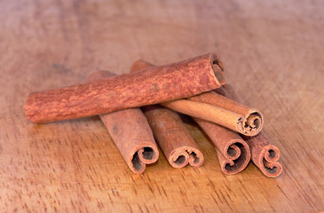 Dry cinnamon sticks on a textured wooden board