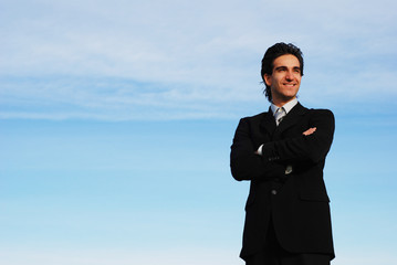 successful businessman is posing against the sky