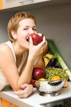 Beautiful girl eating fresh fruits at the kitchen