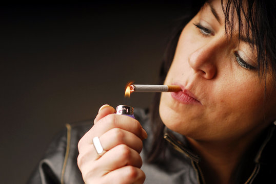 A dark hair woman lighting up her cigarette
