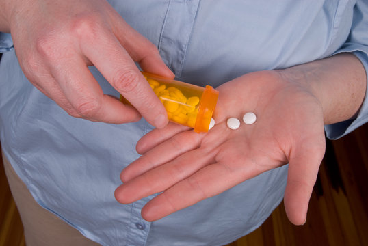 Woman taking pills from a prescription bottle