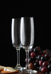 Two empty wine flutes with brie cheese and crackers