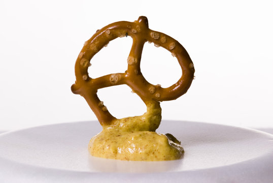 A Baked Twisted Pretzel With A Mustard Dip