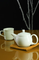 A modern table setting with a teapot and cup
