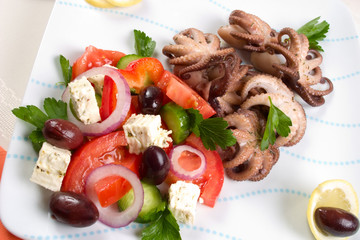 Delicious cooked octopus in red wine dish and Greek salad.