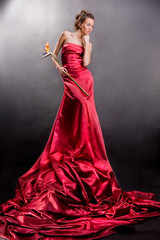 girl in a long red dress holds an exotic flower in a hand