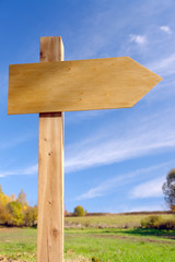 Blank wooden signpost over blue sky