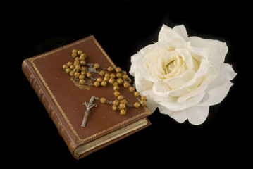 rosary and bible with white rose on black