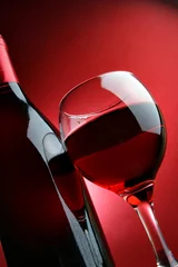 Photo sur Plexiglas Vin Still-life with bottle and glass of wine over red background