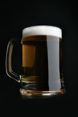 Dark beer with froth over black background
