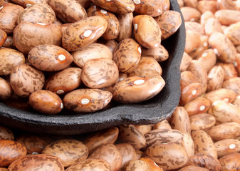 Close up of organic pinto beans in a cast iron laddle.