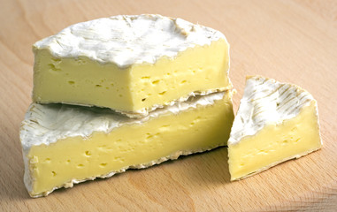 Pieces of camembert cheese on wooden plate