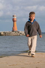 A small boy walking near the sea