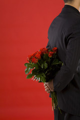 Businessman holding bouquet of roses behind his back