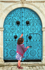 little girl knocking to a blue door - tunisia - africa