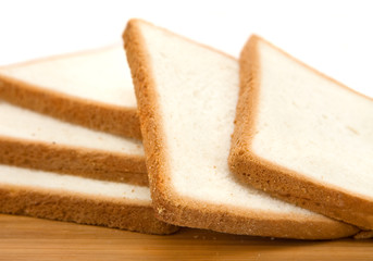 Slices of fresh sandwich bread on wooden board.