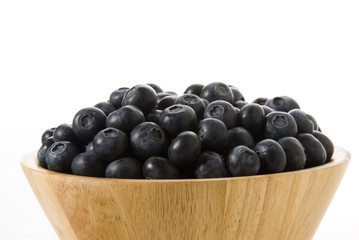 blueberries on a wooden bowl , isolated over white background