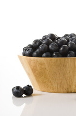blueberries on a wooden bowl , isolated over white background