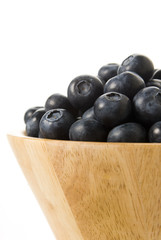 blueberries on a wooden bowl , isolated over white background
