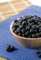 blueberries on a wooden bowl over blurry background