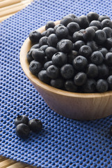blueberries on a wooden bowl  over blurry background