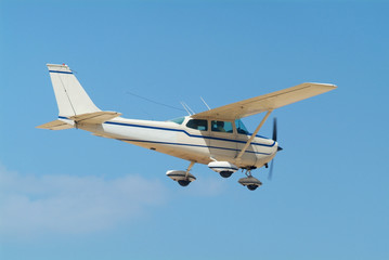 Light, white airplane mid-air on a blue sky background
