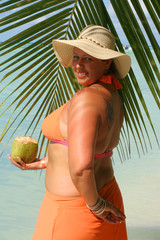 voluptuous woman holding coconut with palm backdrop 