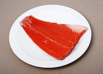 Raw salmon filet on a white plate