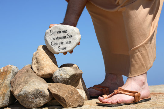 A man holds a white rock inscribed with a bible verse