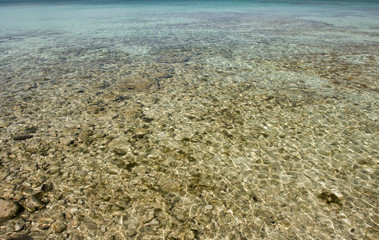 pebbles in the shallow clear tropical water as a background