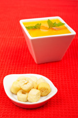 Bread croutons and carrots puree on red mat. Shallow DOF