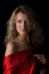 Fototapeta premium Young woman in red silk isolated in the black background
