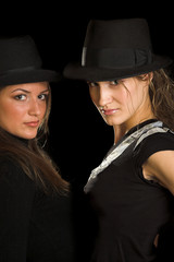 two girls in black hats on black background