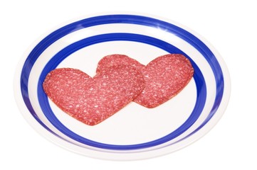 two red salami hearts on the plate isolated on white background