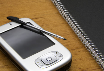 PDA with stylus lying on an office desk.