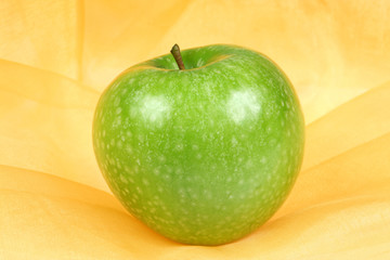 Green, healthy, organic apple on a textile background
