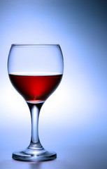 Footed glass of red wine over blue background