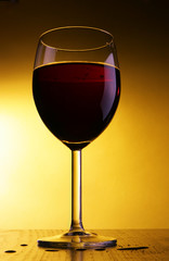 Single glass of red wine over yellow background