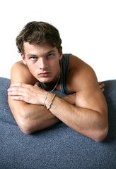 Obraz premium Sexy muscular man leaning on the sofa isolated on white