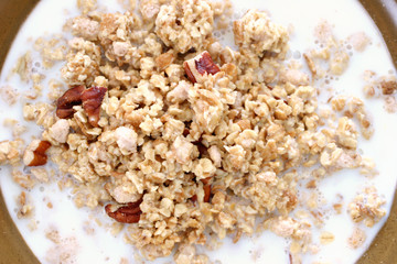 Bowl of crumbly wheat and corn cereal with nutty bits in milk