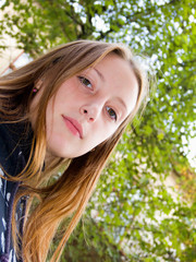 The lovely girl stands under a green tree