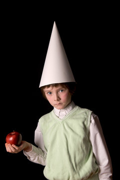 Sad young boy in a dunce cap