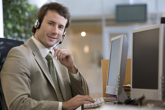 Businessman talking on a headset at his computer