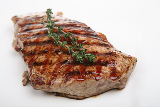 Freshly griddled sirloin steak resting on a white plate