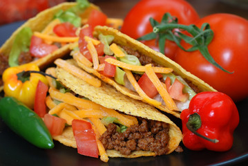 Tacos on plate with tomatoes, habanero and serano peppers.